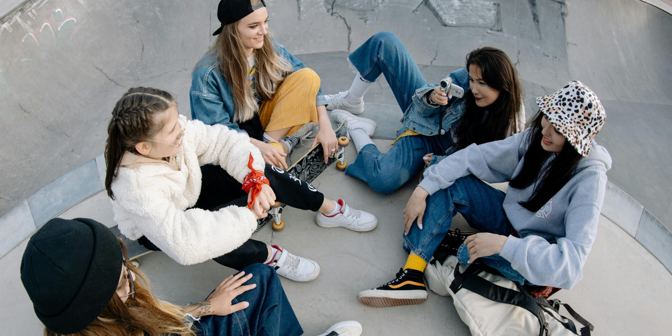 Five young women enjoy time together at a skate park, sharing laughter and friendship.