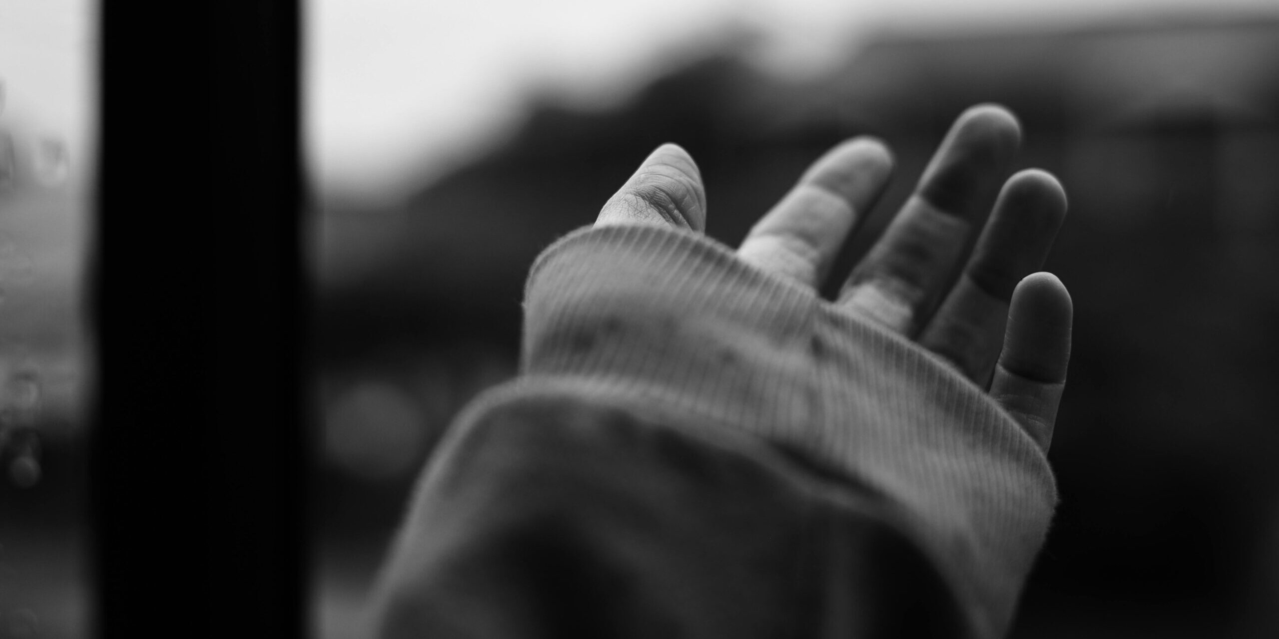 Black and white photo of a hand reaching out, creating a sense of longing and connection.